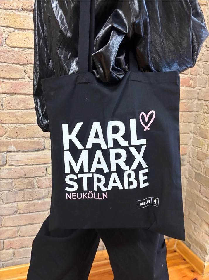 Schwarzer Stoffbeutel mit weißem „Karl-Marx-Straße Neukölln“-Aufdruck und rosa Herz.