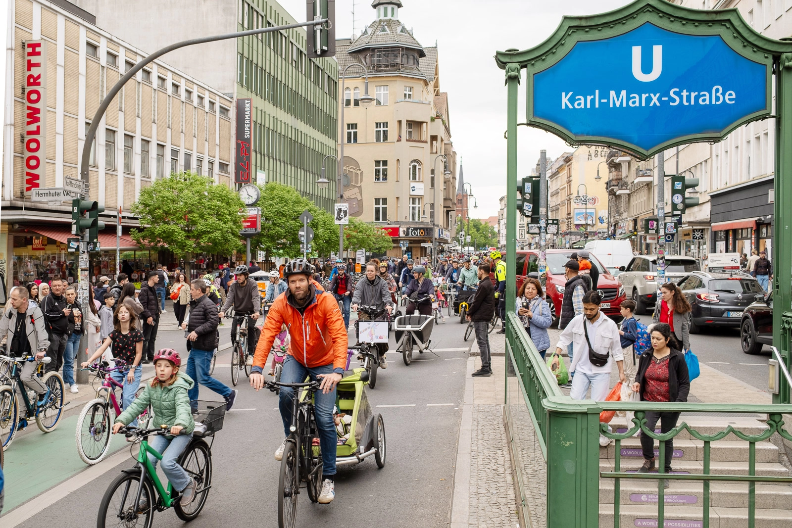 kms-sonne_DSCF6521 Fahrraddemo auf der Karl-Marx-Straße vor dem U-Bahnhof Karl-Marx-Straße mit vielen Radfahrenden und Passanten.
