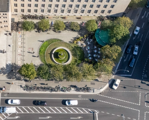 Rathausvorplatz mit Rundbrunnen, Bäumen und Außengastronomie; das Sondernutzungskonzept Neukölln ist veröffentlicht.